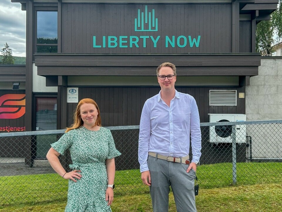 Camilla Moen og Einar Uvsløkk foran brunt bygg med Liberty Now-logo.
