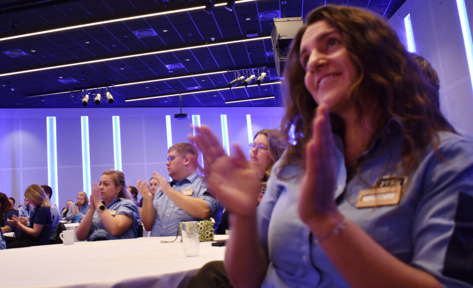 De ansatte i JYSK-butikkene kan glede seg over en bonus på over 15,1 millioner norske kroner. mennesker i Jyskuniform, sitter i en sal og klapper