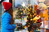 Side view of a smiling female with long hair walking in the city street admiring the Christmas atmosphere in the town and looking at the store window decorated by Christmas decoration looking for presents