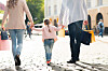 Familie med barn går i en bygate med handleposer.