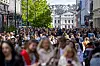 Mange mennesker går i Karl Johans gate i Oslo med Oslo S i bakgrunnen.