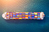 Aerial view of a container ship with colorful cargo containers sailing in dark blue water.