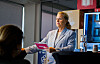 Marianne Bjarstad holder et innlegg innendørs foran publikum med presentasjonsmateriell i bakgrunnen.