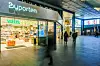 Innendørs passasje med Vitusapotek, butikker og flere gående personer.