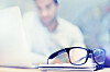 Blur, notebook and glasses on desk with man in office for planning, schedule and agenda on table. Laptop, eyewear or worker copywriting with diary journal for business, administration or email on web.