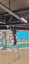 Kim-Harald Laupstad står på en høy gardintrapp inne på senteret. Normalbutikken i bakgrunn
