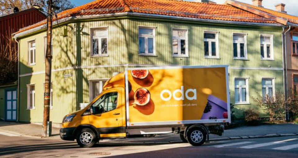Gul Oda-varebil, foran et grønt hus.
