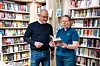 bokhandel, hyller med mange bøker, to personer som ser i en bok